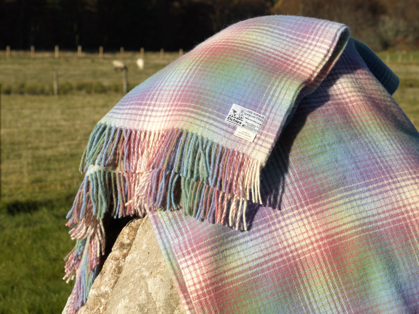 The Elchies Farm 'Borealis Wool Blanket' draped on a rock in the sun.