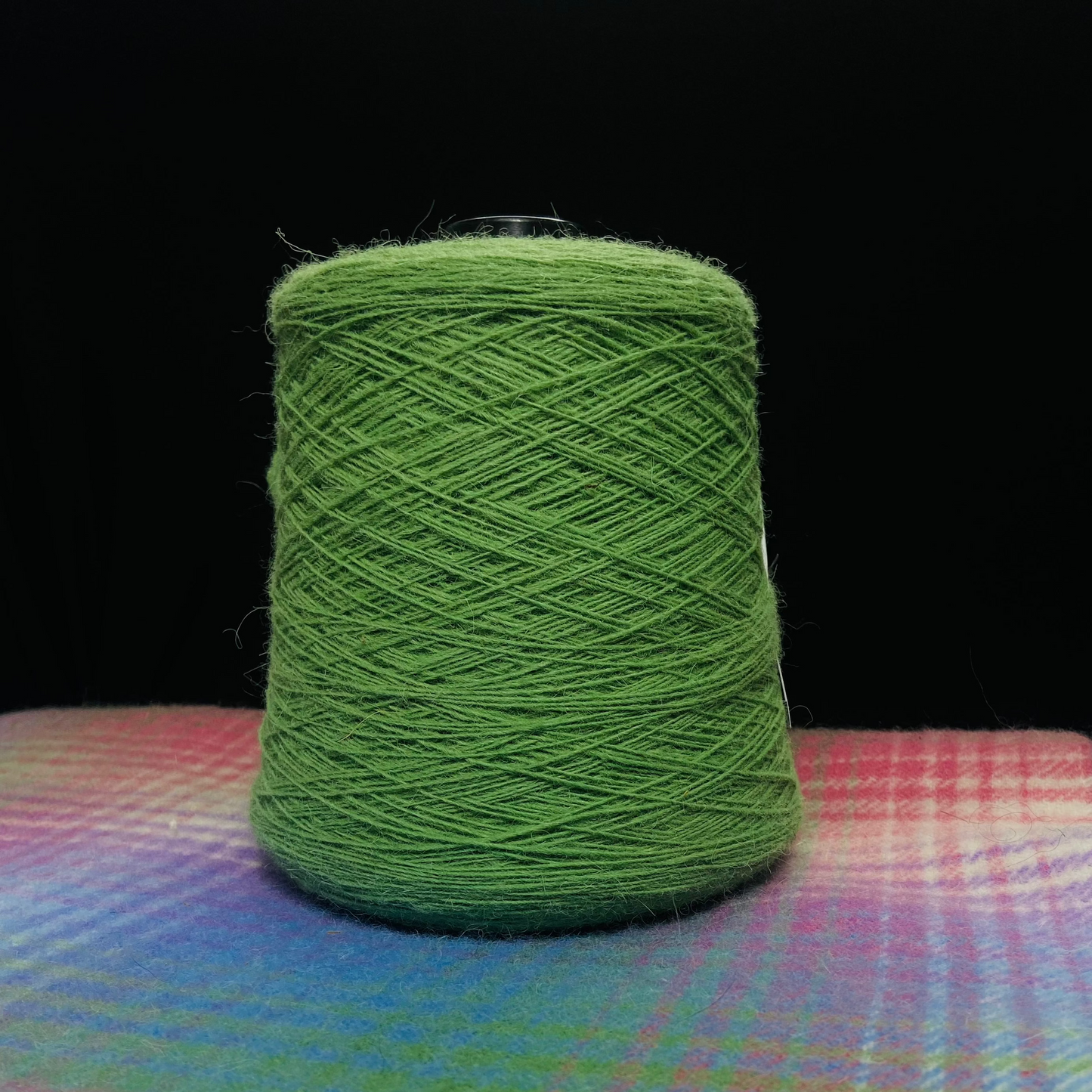 A cone of Elchies Farm Wool in the shade 'Green'.